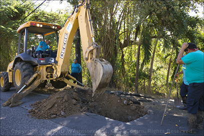 Water Utility Backhoe Digging up Driveway to Fix Water Mains Leak in Coamo, Puerto Rico